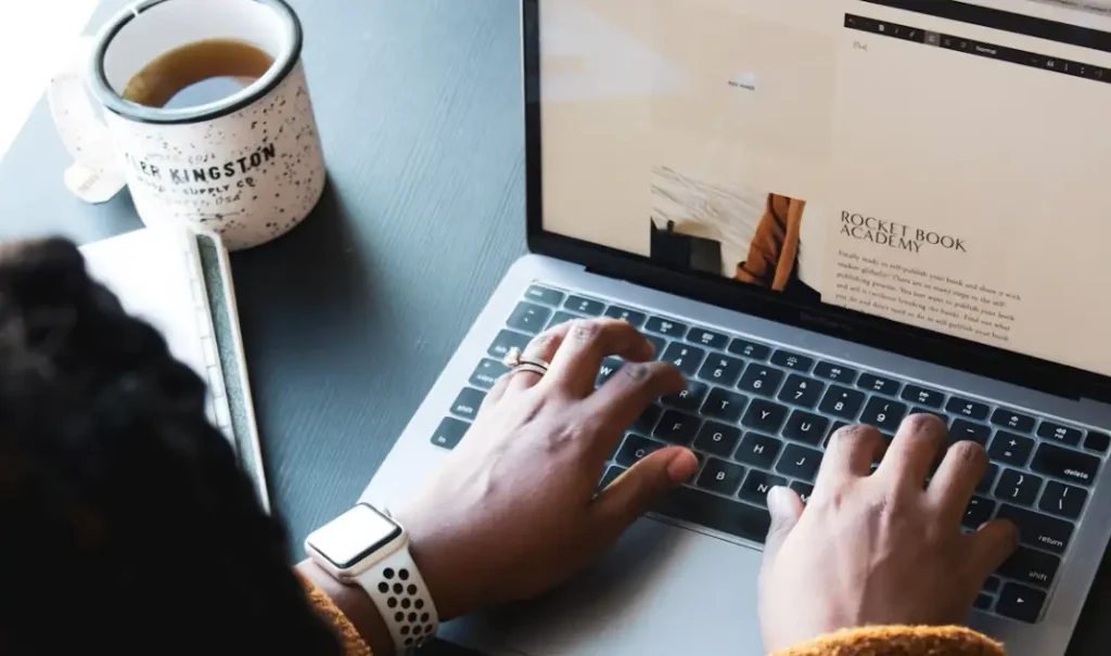 freelance de dos écrivant sur son pc avec un mug à gauche